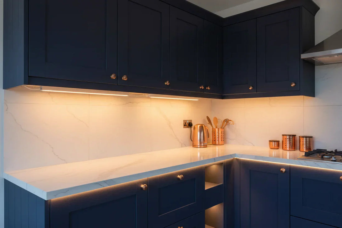 Modern UK kitchen with warm white LED under-cabinet lighting illuminating a marble countertop, illustrating wireless vs hardwired lighting options
